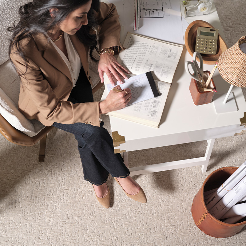 Designer reviewing architectural plans in a workspace featuring Pottersville carpet in Pale Oak